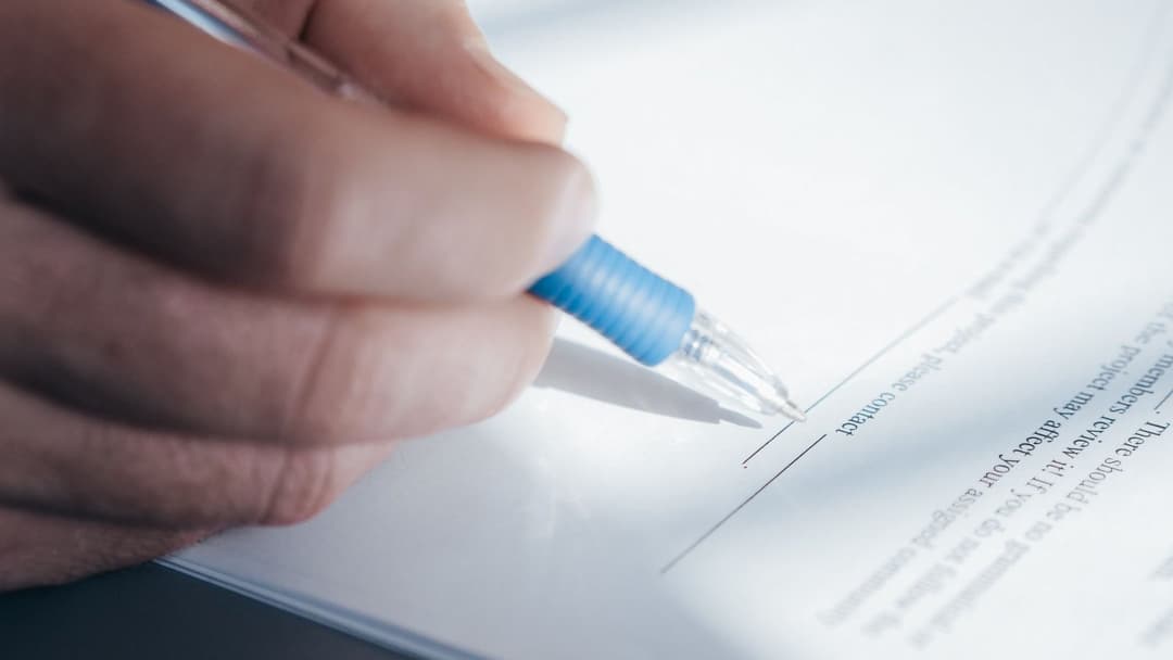 Main signant un document administratif au stylo, formulaires DC1 et DC2 d'un marché public