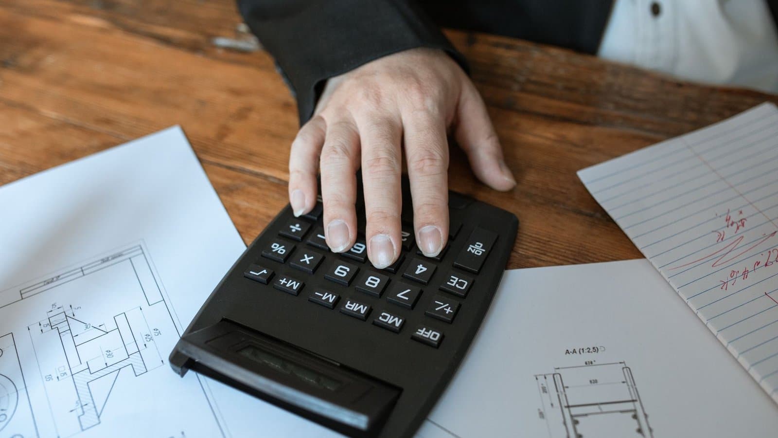 Calculatrice posée sur des plans techniques, chiffrage avant l'usage d'un logiciel de devis bâtiment