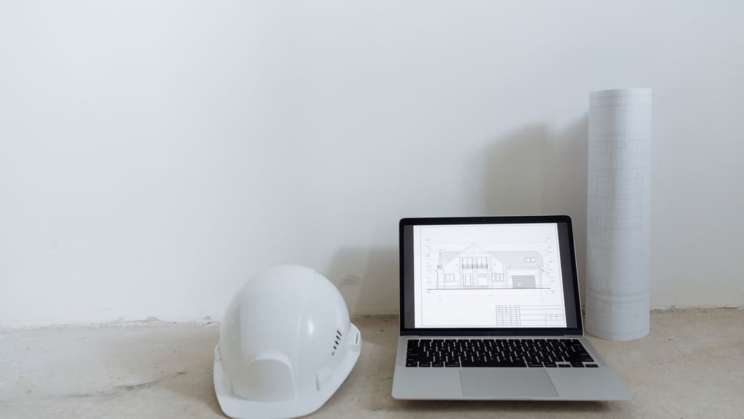 Ordinateur portable, casque et plans sur un poste de travail, usage d'un logiciel d'appel d'offre BTP