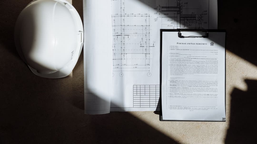 Documents de chantier et casque de sécurité sur un bureau, dossier de réponse à un appel d'offre BTP