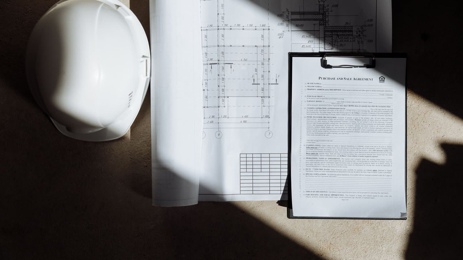 Documents de chantier et casque de sécurité sur un bureau, dossier de réponse à un appel d'offre BTP