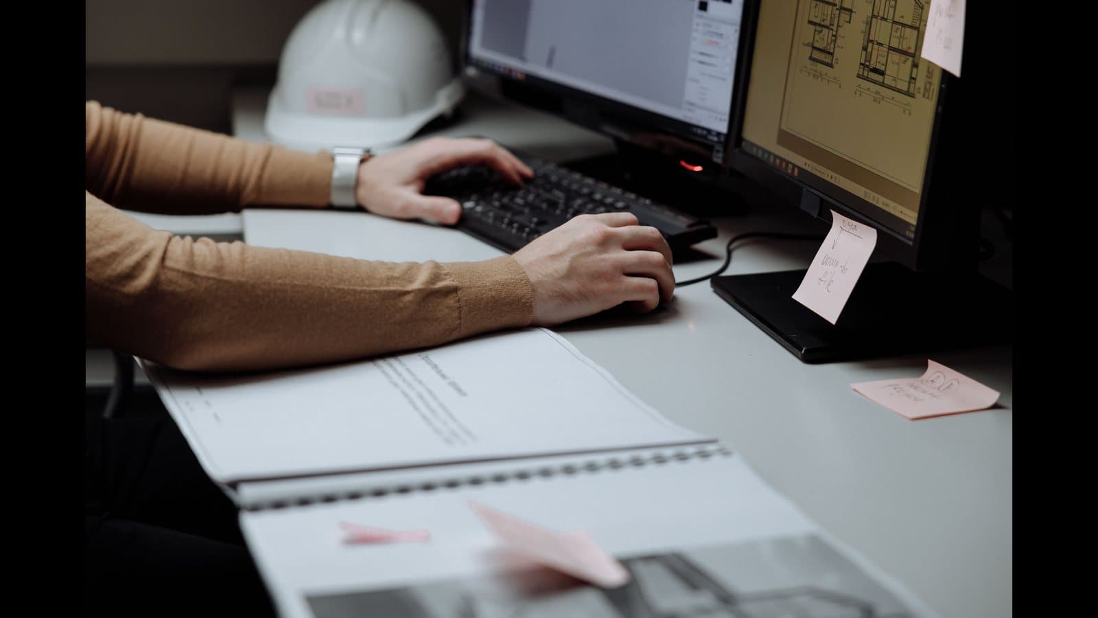 Professionnelle du bâtiment préparant un devis sur ordinateur à partir de plans