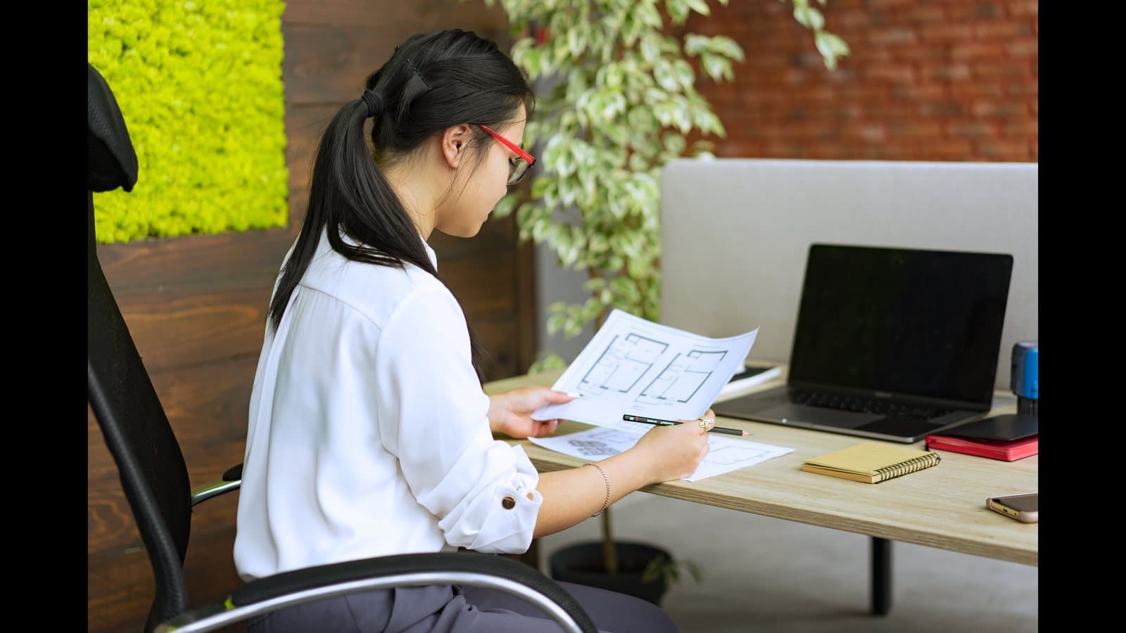 Professionnelle analysant un document de notation et des plans de construction
