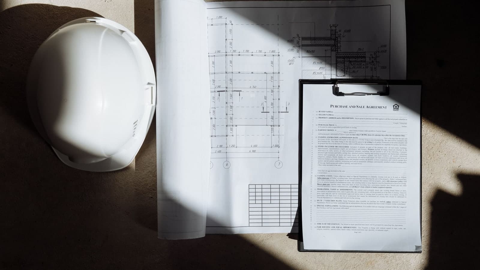 Plans de construction, contrat et casque de chantier pour contrôler une DPGF de marché public