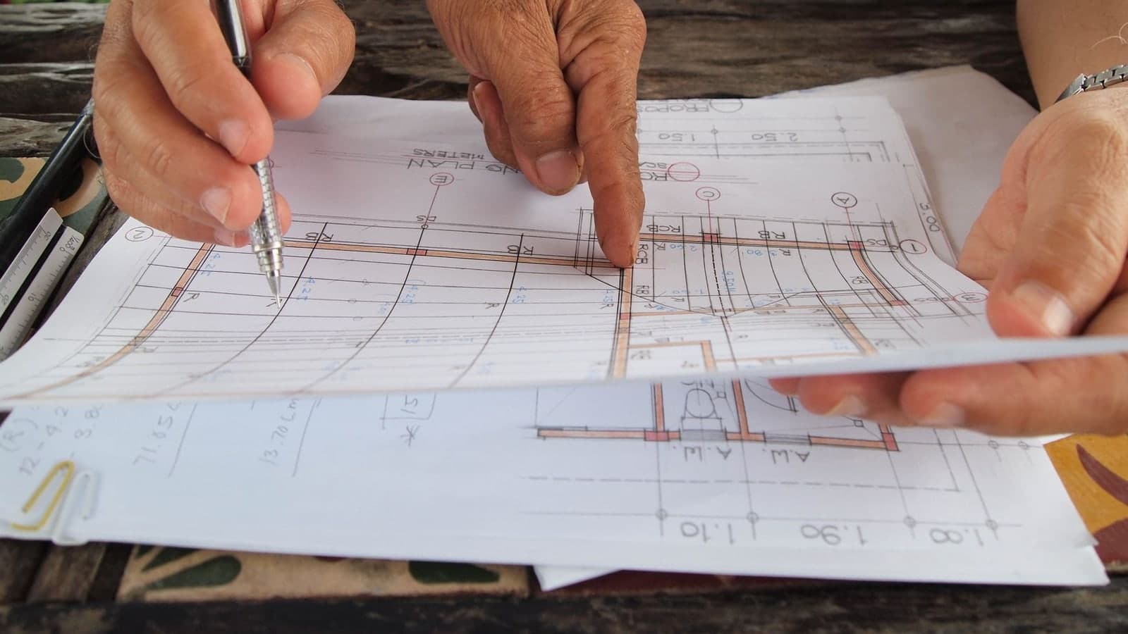 Architectes contrôlant des dimensions et quantités sur des plans techniques